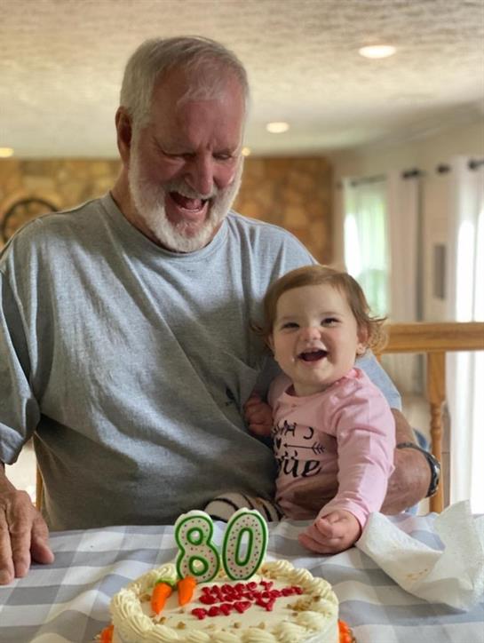 Grandfather and granddaughter share a joyful moment while celebrating a special birthday indoors.