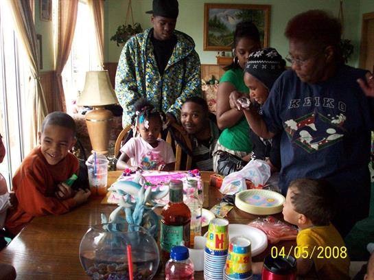 A warm family celebration unfolds in a living room filled with joy, food, and shared moments.