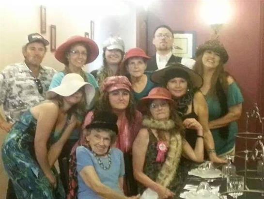 A diverse group of friends poses together wearing various stylish hats at a lively event.