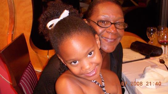 A young girl playfully smiles with her grandmother at a joyful family event.