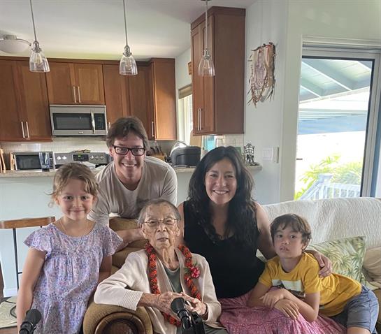 Joyful family time captured with grandmother, parents, and young kids in a warm living room setting.