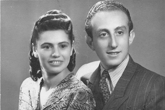 A couple smiles warmly while dressed in stylish vintage clothing, showcasing their connection.