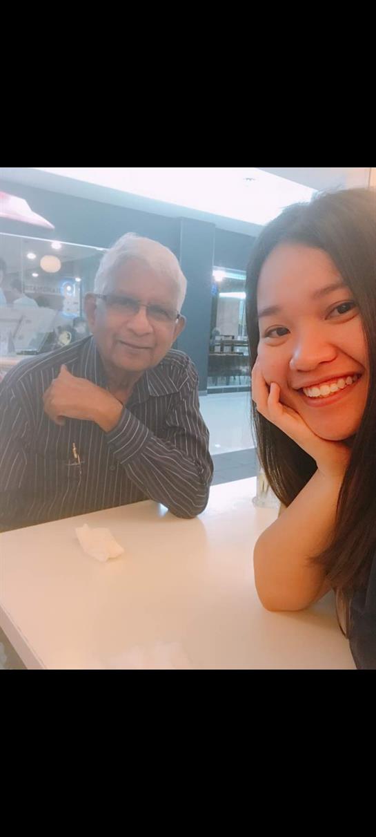 A young woman and an older man share a joyful moment while enjoying their time at a cafe.