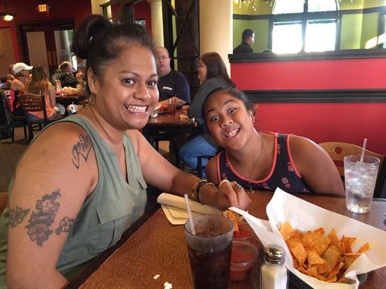 A mother and her son share a joyful moment while eating lunch at a crowded restaurant.