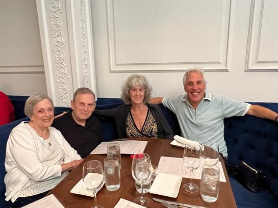 Four friends sit around a table, laughing and sharing stories during dinner time.