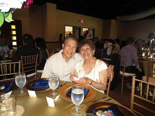 A couple enjoys a joyful moment together at a festive gathering, surrounded by friends.