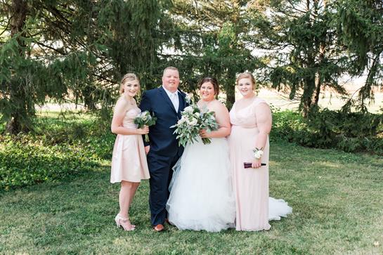 Four friends pose happily together at a wedding in a lush garden surrounded by greenery.