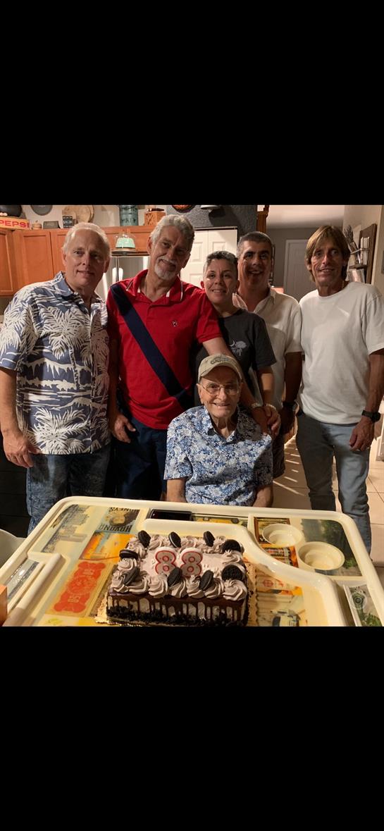 Group of friends gathers around a birthday cake, sharing joyful moments and smiles in a bright room.