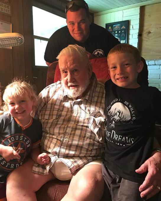 Two kids play and smile with an elderly man in a cozy home, enjoying family time.