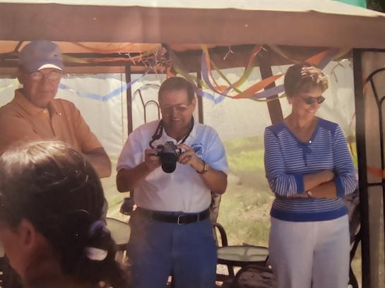 Visitors listen to a guide while taking photos at a scenic outdoor location during a sunny day.
