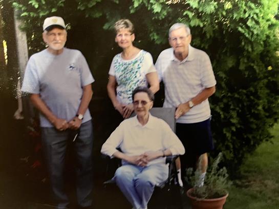 Four relatives pose happily together in a lush garden, enjoying a joyful afternoon.