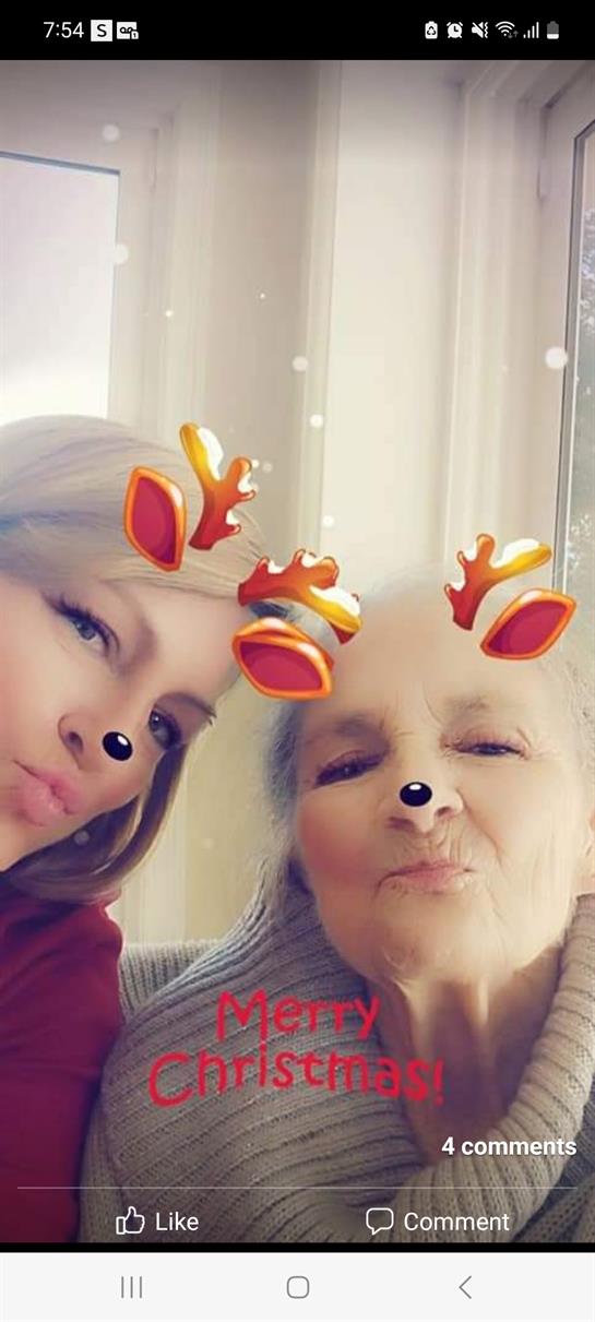 A joyful moment of a grandmother and granddaughter sharing smiles with reindeer filters.