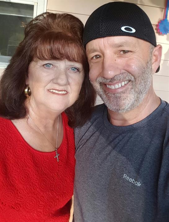 Two smiling individuals capture a joyful moment together while enjoying their time outside.