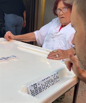Two people engage in a lively game of dominoes outdoors in a casual setting.