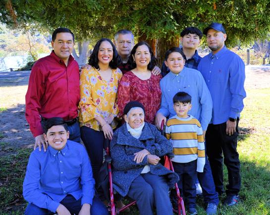 A close-knit family enjoys a sunny day at the park, smiling and posing together for a group photo.