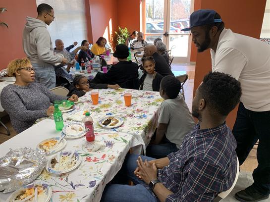 Friends and family gather around a table, sharing laughter and stories in a lively mood.