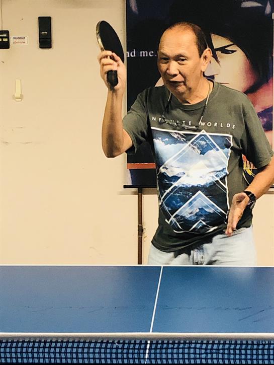 A player stands confidently at a table tennis table, preparing to serve during a competitive match.