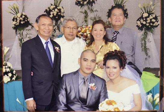 A joyful family gathering celebrating a wedding with the couple in formal attire.