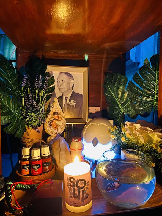 Altar adorned with candles, flowers, and a photograph, creating a peaceful atmosphere indoors.