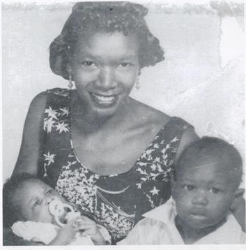 A joyful woman holds her infant and sits beside her toddler in a warm atmosphere.