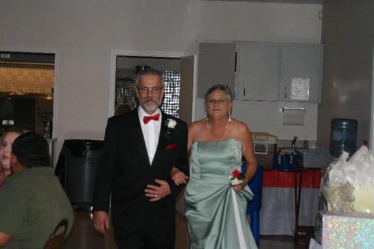 An elegant couple in formal wear strolls joyfully together at a festive gathering.