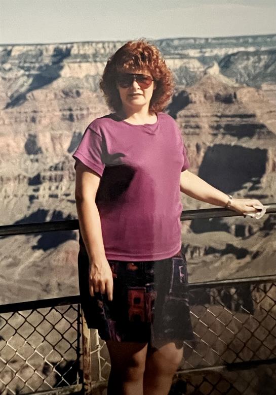A woman stands confidently at the Grand Canyon, admiring its stunning landscape and colors.