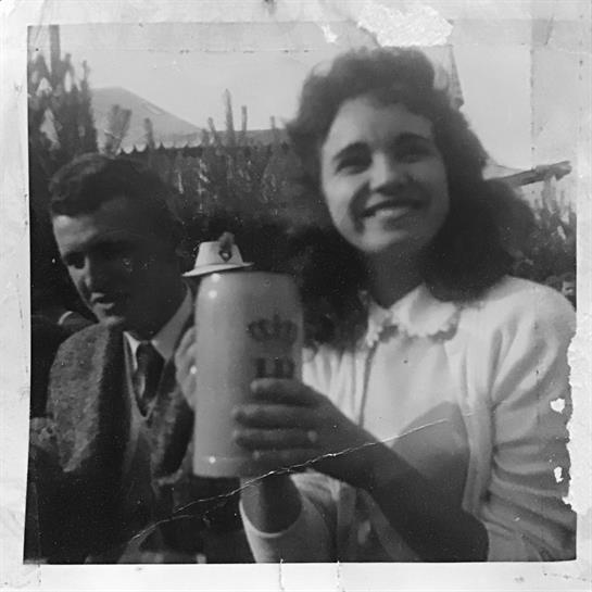 A smiling woman poses with a large drink while a man sits beside her, enjoying the event.