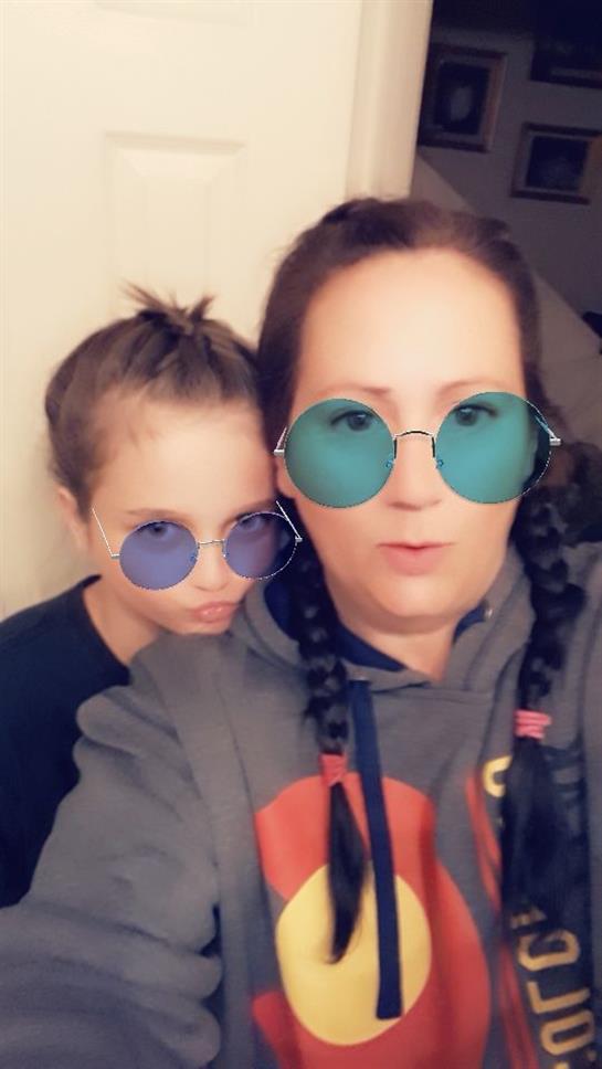 A mother and her child pose together playfully wearing stylish round sunglasses, smiling.