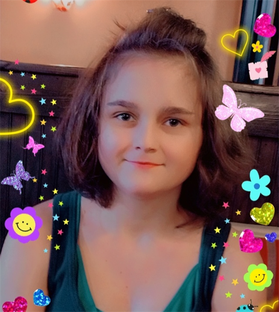 A cheerful girl with short hair smiles amid colorful decorations and playful patterns.