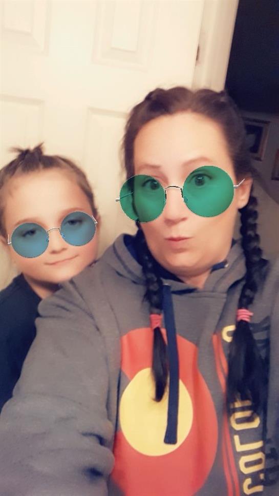 A woman and a child pose together with playful expressions, wearing colorful sunglasses.