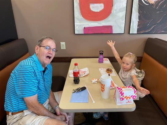 An elderly man and a young girl share a joyful lunch in a cozy dining space.