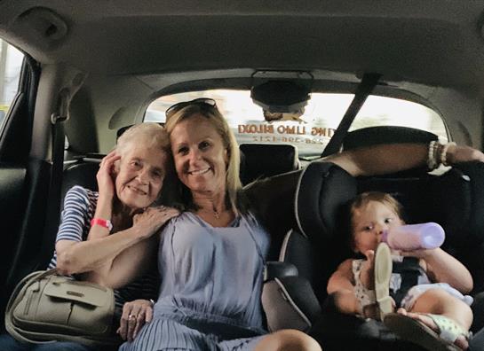 Three generations of women pose happily inside a car, sharing joyful moments together.