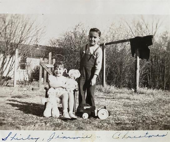 Two kids are playing outside in a grassy area, showcasing friendship and joy on a sunny day.