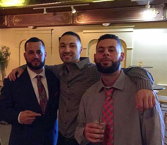 Three friends pose together, smiling and dressed well, at a celebration in a lively setting.