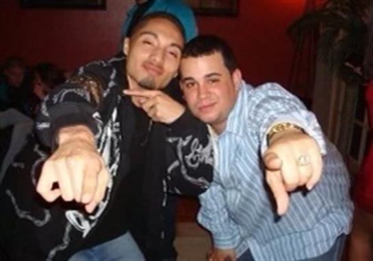 Two men share a fun moment together, pointing at the camera in a vibrant atmosphere.