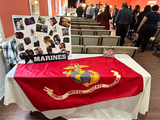 A gathering of community members celebrates local Marines with a flag and memorabilia on display.
