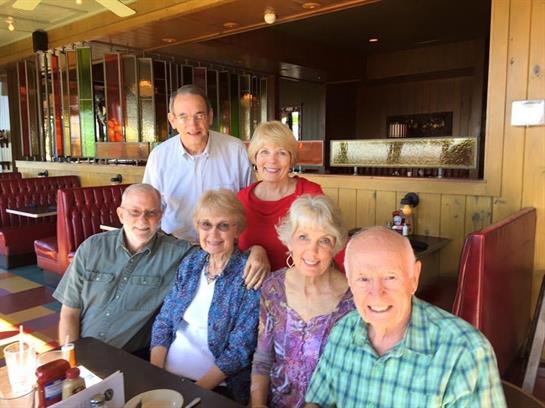 Group of six friends enjoying a lively lunch at a cozy restaurant with vibrant ambiance.