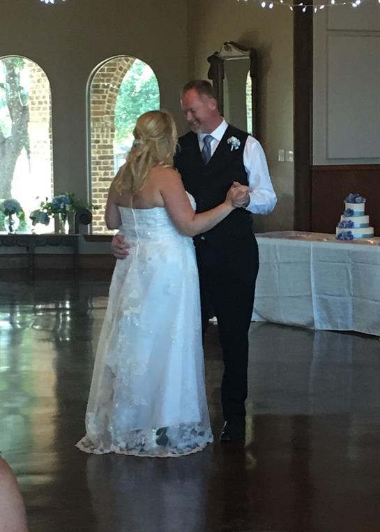 A couple dances closely at their wedding reception, surrounded by elegant decor and guests.
