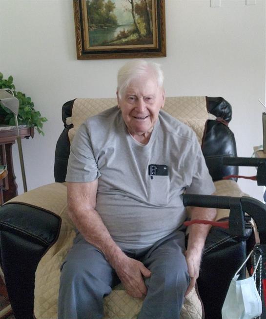 Senior man enjoys a moment of joy, seated in a comfortable armchair decorated with plants.