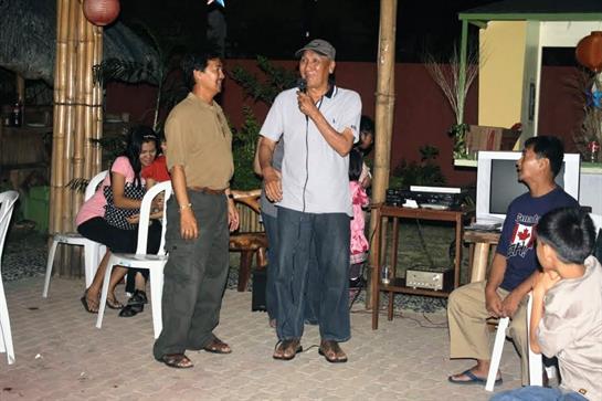 Two men engage in a lively performance at a casual outdoor event as guests enjoy the atmosphere.