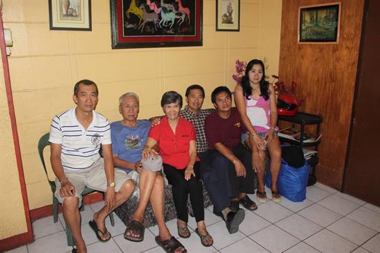 A group of seven people enjoying time together at home, sharing stories and laughter.
