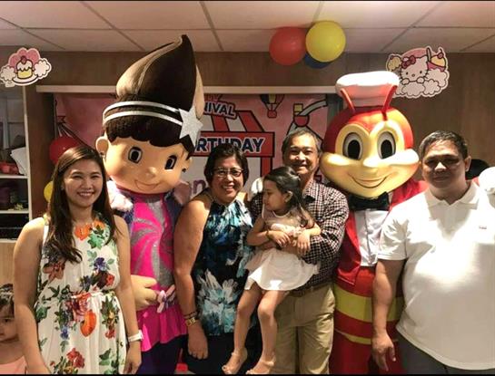 Family and friends gather to celebrate a birthday with lively mascots and cheerful expressions.