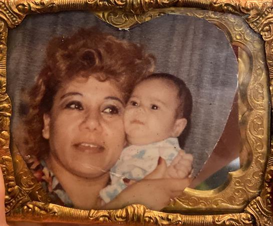 A woman smiles while holding a baby close, captured in an ornate frame, radiating love and warmth.