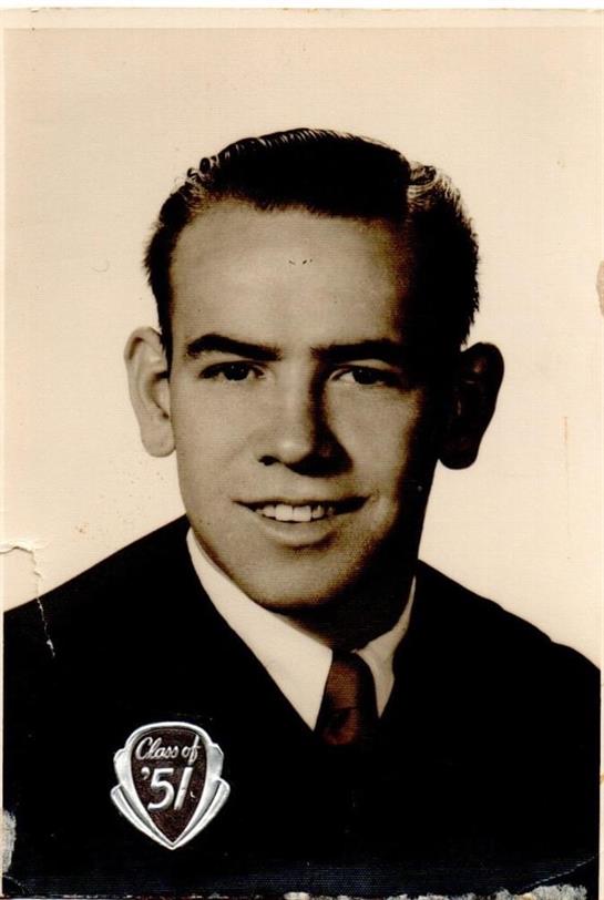 A young man confidently smiles in a formal suit and tie, showcasing his neat hairstyle.
