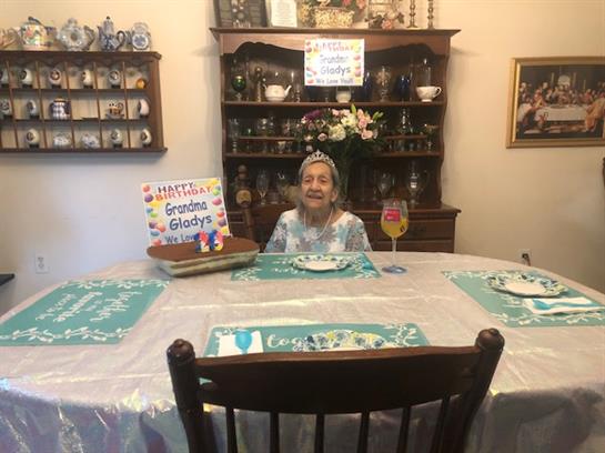 Family gathers around a decorated table to celebrate Grandma Gladys' special day with joy.