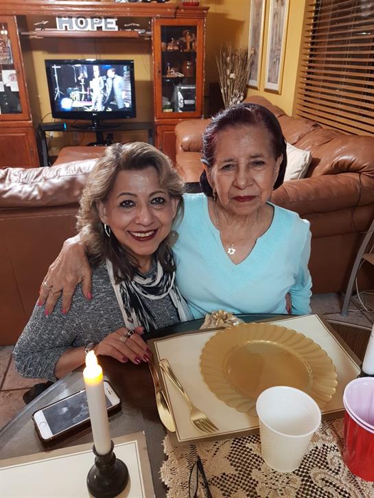 Two friends smile warmly while sharing a meal in a comfortable living room setting.