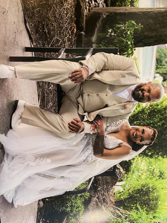 Newlywed couple poses joyfully amid greenery, showcasing love and happiness on their special day.