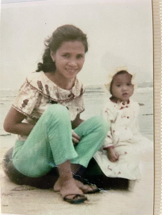 Two women relax on the beach, one smiling and both enjoying a joyful moment together.