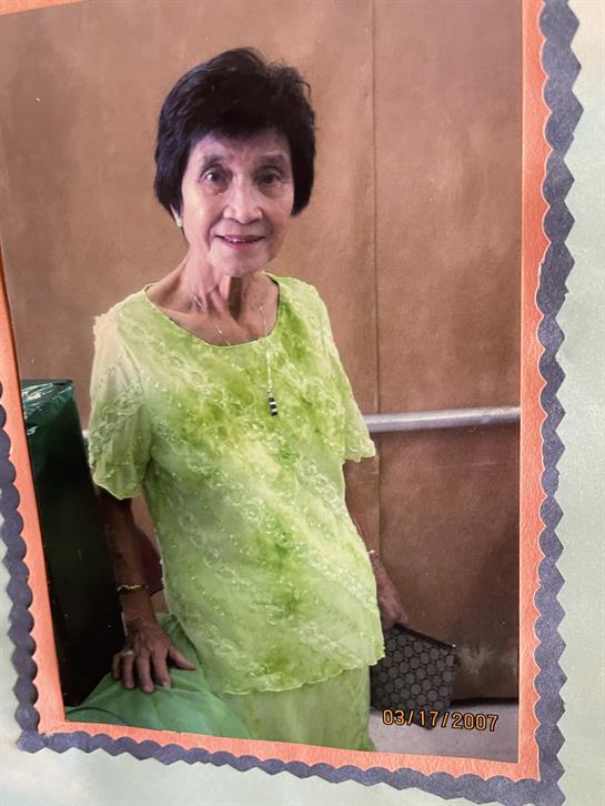 A joyful senior woman poses in a bright green outfit at a local gathering, showcasing warmth.