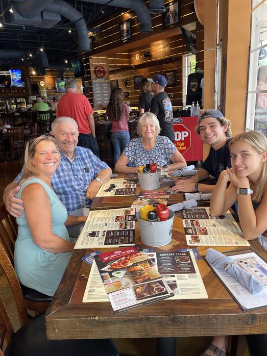 A cheerful family gathers around a table, sharing a meal and laughter at a vibrant restaurant.
